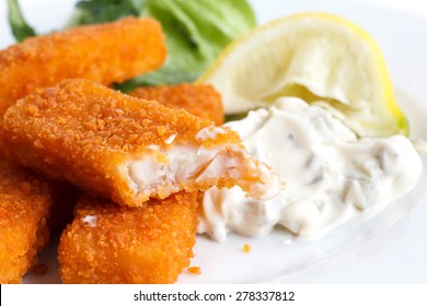 Half Eaten Fish Fingers With Lemon And Tartar Sauce.