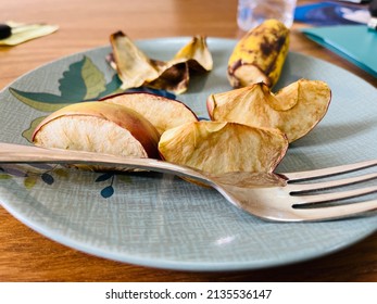 A Half Eaten Plate Of Old Sliced Apple And A Fork.