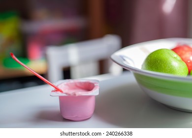 Half Eaten Yogurt And Bowl Of Fruits On Table