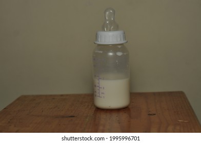 Half Empty Bottle Milk Of Baby Pacifier In A Wooden Table