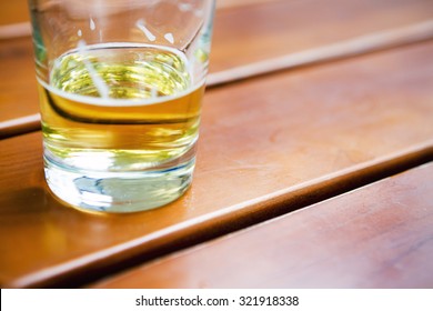 Half Empty Glass Of Beer On Wooden Table