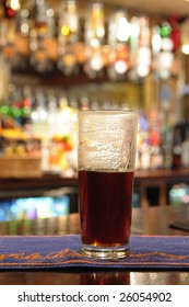 Half Empty Pint Glass Of Beer Sitting On Bar In A Pub