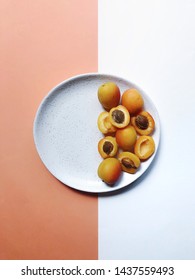 Half Empty Plate With Apricots On A White-orange Background.