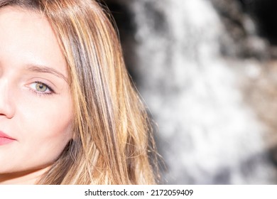 Half Face Of Blonde Woman In Nature With A Waterfall Behind