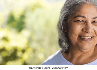 Half face of of happy biracial senior woman smiling in sunny garden, copy space. Retirement, wellbeing and senior lifestyle, unaltered. - Powered by Shutterstock