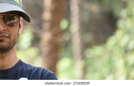 Half Face Of Man Wearing Glasses With Natural Green Blurred Background, Ample Space For Text