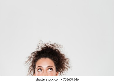 Half Face Of Pretty Curly Woman Looking Up Over Gray Background