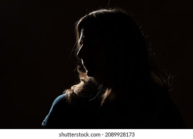 Half face of unrecognizable woman portrait in shadow shrouded in darkness isolated on black background with wide copy space, concept of anonymity to hide identity