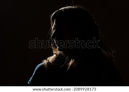 Half face of unrecognizable woman portrait in shadow shrouded in darkness isolated on black background with wide copy space, concept of anonymity to hide identity