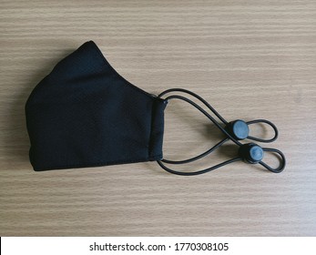 A Half Folded Cloth Mask Isolated On Wooden Ground, Very Comfortable Wearing When Out In Public To Protect Against Covid-19 Or Corona Virus, New Normal.