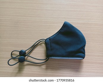 A Half Folded Cloth Mask Isolated On Wooden Ground, Very Comfortable Wearing When Out In Public To Protect Against Covid-19 Or Corona Virus, New Normal.