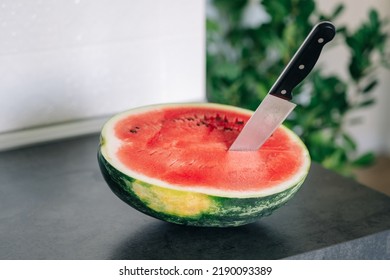 Half Of Fresh Sliced Watermelon With Knife On A Kitchen Table After The Refrigerator. Authentic Lifestyle. Home Cooking, Preparation Of Organic Food.