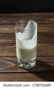 A Half Full Glass Of Milk Is On The Table. Vertical Photo.