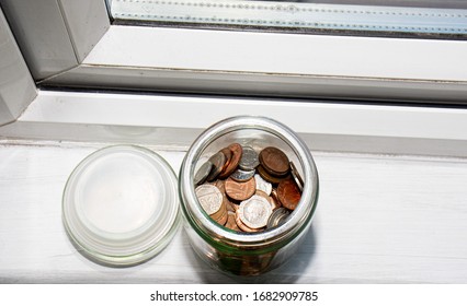 A Half Full Jar Of Money On A Window Sill