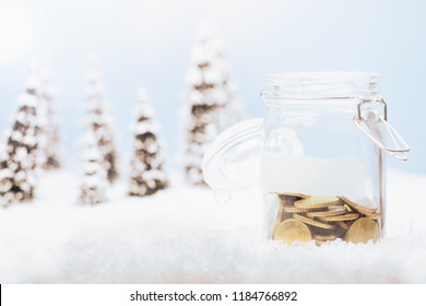 Half Full Money Jar Glass With Coins For Savings In Christmas Holiday Season Background Of Snow Landscape