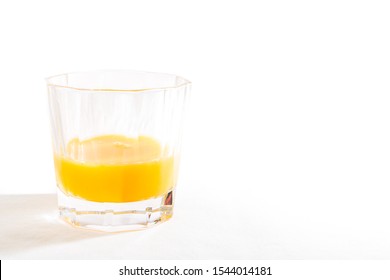 A Half Full White Crystal Glass Tumbler Filled With Orange Juice Is Isolated On A White Background - Wide Angle Landscape View.