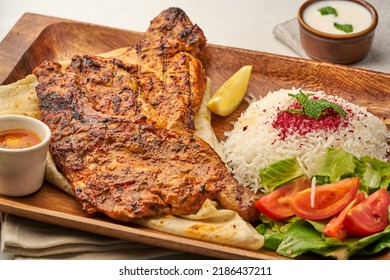 Half Grilled Chicken With Rice Salad, Onion, Tomato, Lime And Pita Bread Served In A Dish Isolated On Grey Background Side View Of Fastfood