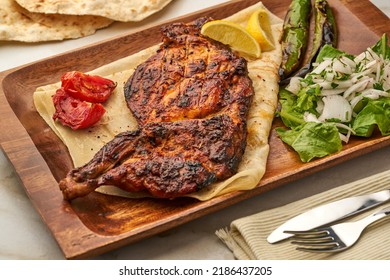 Half Grilled Chicken With Salad, Onion, Tomato, Lime And Pita Bread Served In A Dish Isolated On Grey Background Side View Of Fastfood