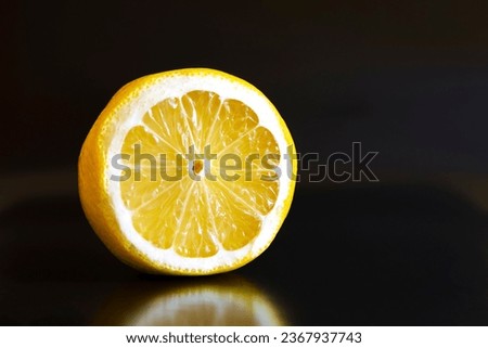 Half a lemon lies on a black background.