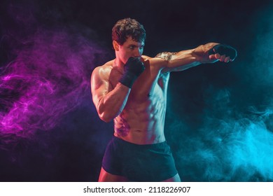 Half length of aggressive athlete boxer who training and practicing swing Isolated on smoke background. Concept of sport, healthy lifestyle. 