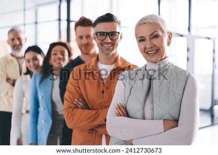 Half length of confident corporate director posing in office with blurred involved colleagues at background, Caucasian businesswoman looking at camera during working time with experienced investors