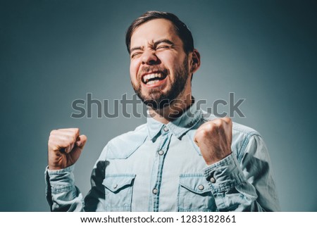 Half length portrait of casually dressed bearded business man holding fists up celebrating his success.