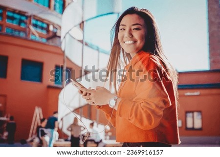 Half length portrait of cheerful asian hipster girl strolling around city streets 