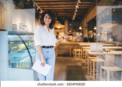 Half length portrait of cheerful Caucaisan manager feeling success in franchise coffee shop standing in doorway and smiling at camera, happy self employed woman greeting in local cafeteria industry - Powered by Shutterstock