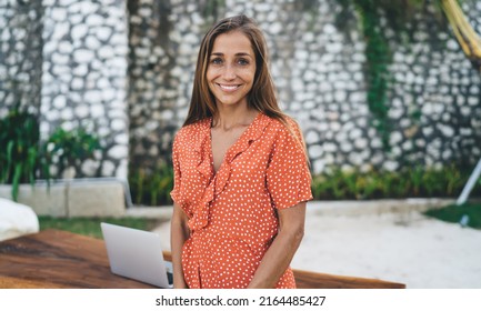 Half length portrait of happy Caucasian hipster girl with cute smile on face looking at camera during leisure pastime, cheerful female millennial in trendy polka dot sundress posing outdoors