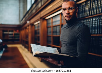 Half length portrait of intellectual professor of history in bifocal eyewear looking at camera while holding literature book in hand for making research of information for new science publication