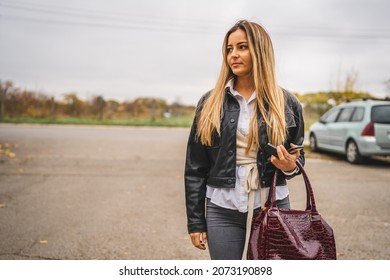 Half length portrait of one young caucasian woman standing alone at the empty parking lot in autumn day looking to the side copy space