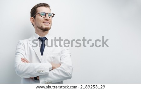Half length studio portrait of a young male doctor smiling with confidence and hands crossed under the chest isolated on white copyspace on the side