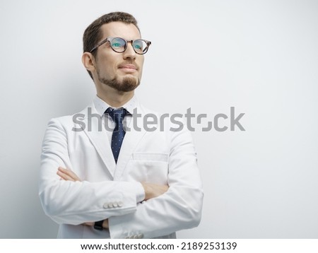 Half length studio portrait of a young male doctor smiling with confidence and hands crossed under the chest isolated on white copyspace on the side