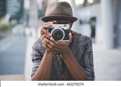 Half length of young beautiful afro black man outdoor in the city holding instant camera, shooting - photography, creative, artist concept - Powered by Shutterstock