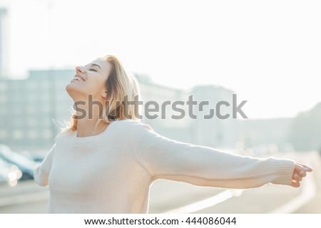 Half length of young beautiful cacuasian woman feeling free with arms wide open in the city back light - liberty, freedom, girl power concept