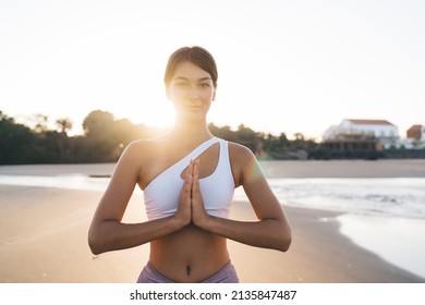 Half length of young Caucasian female yogi breathing during nature mediation at coastline, attractive woman spending time for holistic retreat and healing during yoga practice in namaste outdoors