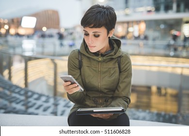 Half length of young handsome caucasian brown straight hair woman using smartphone and tablet, looking downward screen, smiling - multitasking, technology, social network concept concept