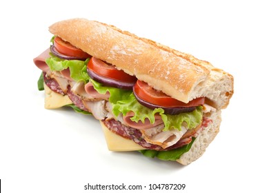 half of long tasty subway baguette sandwich with lettuce, tomatoes, ham, turkey breast, salami and cheese isolated on white background
