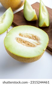 Half melon and sliced pieces of melon on wooden cutting board . - Shutterstock ID 2315244461