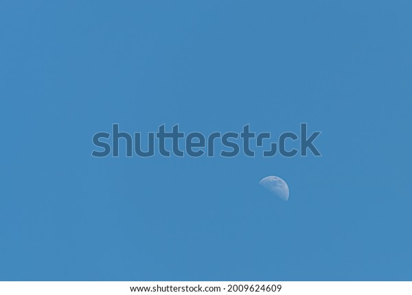 Half Moon in a\
blue, clean sky in\
daytime.
