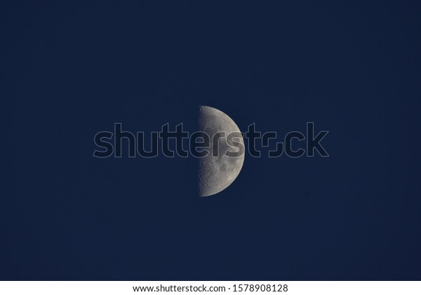 The half moon in blue sky at sunset in December\
of Thailand.