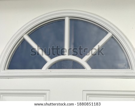 Half moon crescent shaped window with panes on a solid while door
