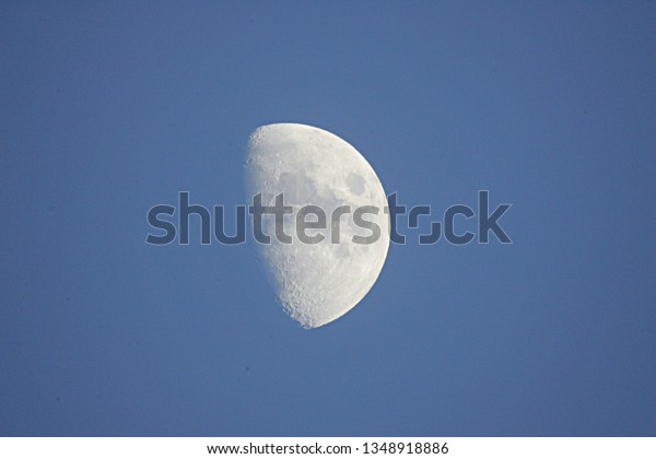 half moon\
during daylight. Half moon on blue\
sky