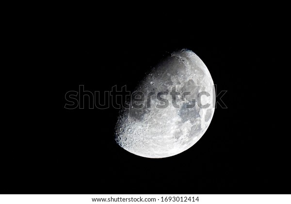 Half moon during the first quarter phase isolated\
against a black sky at\
night