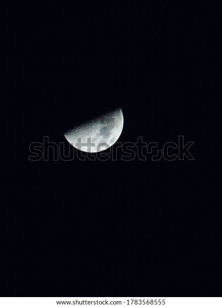 Half moon during the first quarter phase isolated\
against a black sky.