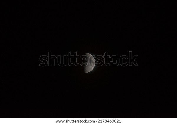 Half moon during the first quarter phase isolated\
against a black sky.