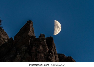 Half moon and rocky mountain in Provo Canyon against dark blue sky at night