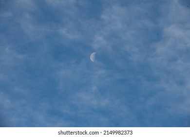 half moon in sky in daytime with wispy clouds environment atmosphere backdrop background or wallpaper horizontal format room for type looking up at clouds in sky with moon in day time 