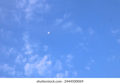 Half moon in sky in daytime with wispy clouds environment atmosphere backdrop background or wallpaper horizontal format room for type looking up at clouds in sky with moon in day time - Powered by Shutterstock