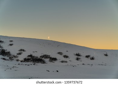 Half Moon Still Visible Over A Snowy Cliff During Sun Rise In Iceland